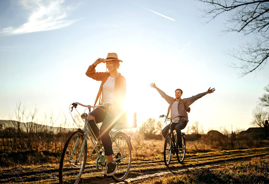 young couple riding bikes outside during sunset