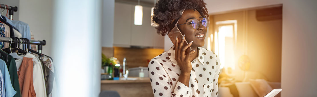 Young african american woman talking on cellphone while working indoors
