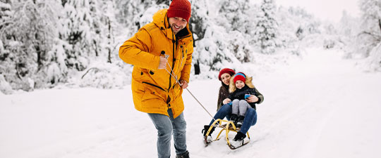 family sledding together in the snow